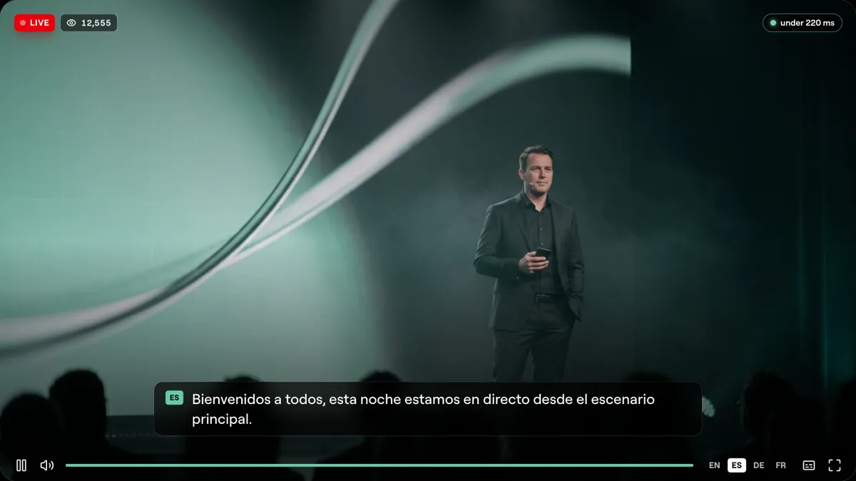The Cliqer Live player showing a speaker on stage with a LIVE badge, a viewer count, a delay badge reading under 220 ms and Spanish captions along the bottom